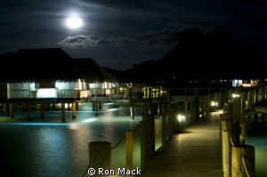 Resort huts over water with main island of Bora Bora in b... by Ron Mack 
